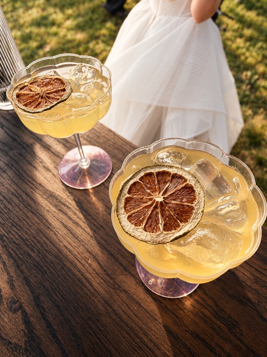 Two golden cocktails in coupe glasses with dried citrus garnishes